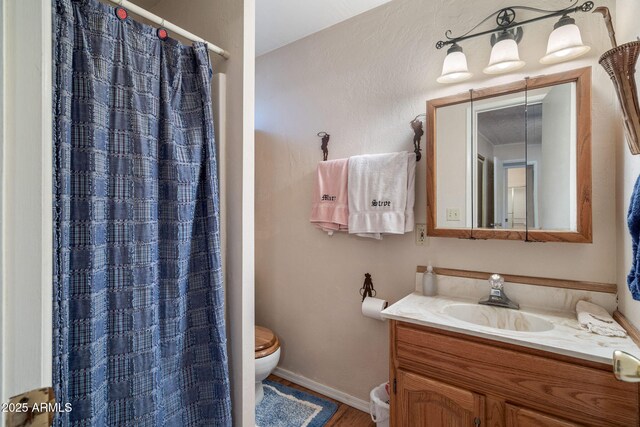 bathroom featuring curtained shower, toilet, vanity, and baseboards