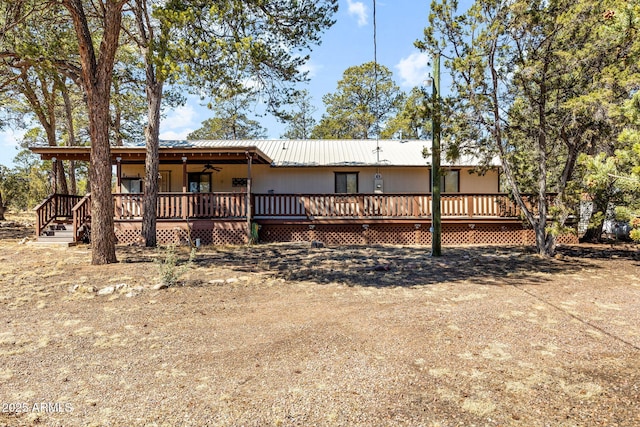 rear view of property featuring a wooden deck and metal roof