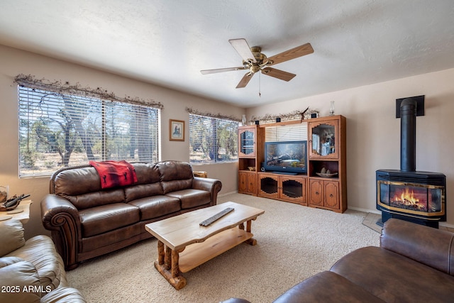 living area featuring ceiling fan, a textured ceiling, a wood stove, and light carpet