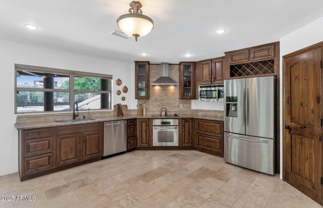 3611 E Ahwatukee Dr, Phoenix, AZ 85044 - kitchen featuring appliances with stainless steel finishes, wall chimney exhaust hood, light stone counters, tasteful backsplash, and glass insert cabinets