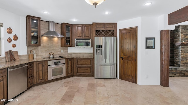 3611 E Ahwatukee Dr, Phoenix, AZ 85044 - kitchen featuring appliances with stainless steel finishes, wall chimney range hood, backsplash, light stone counters, and glass insert cabinets