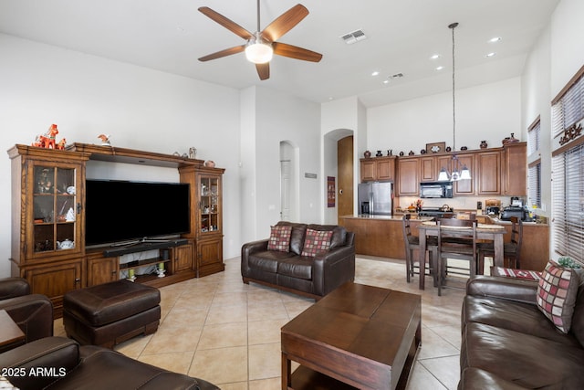 living area with arched walkways, visible vents, a high ceiling, a ceiling fan, and light tile patterned flooring