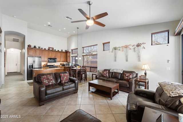 living area with light tile patterned floors, visible vents, arched walkways, and a ceiling fan