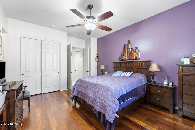 bedroom featuring a ceiling fan, wood finished floors, visible vents, and multiple closets