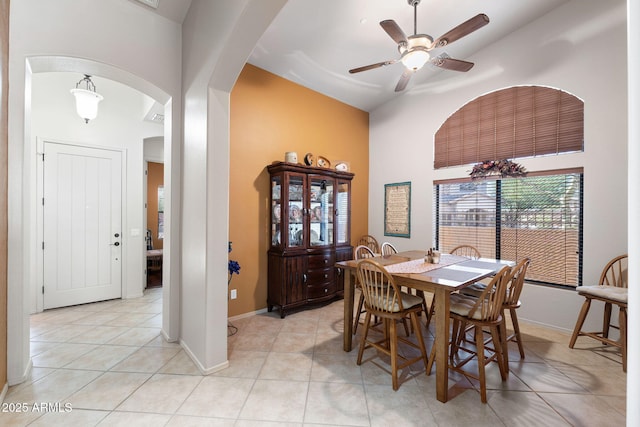 dining space with baseboards, arched walkways, ceiling fan, and light tile patterned flooring