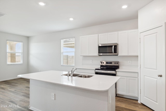 kitchen with sink, light hardwood / wood-style flooring, appliances with stainless steel finishes, white cabinetry, and an island with sink