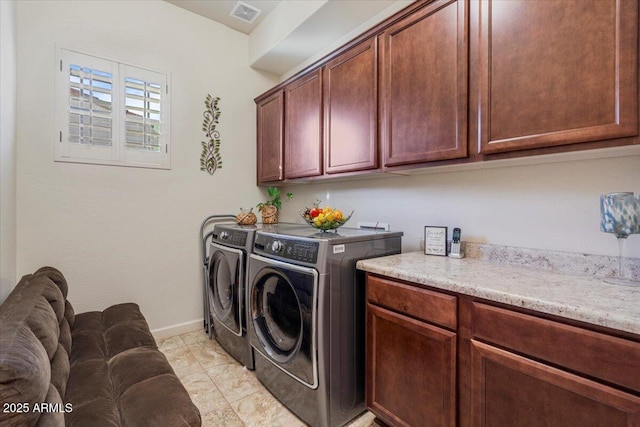 washroom featuring baseboards, cabinet space, visible vents, and washing machine and clothes dryer