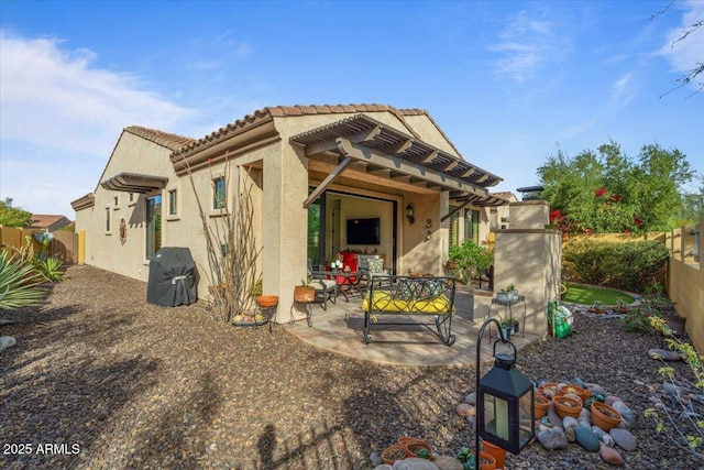 rear view of house featuring stucco siding, a fenced backyard, a tiled roof, and a patio