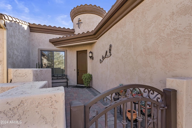 exterior space with a gate, a tiled roof, and stucco siding