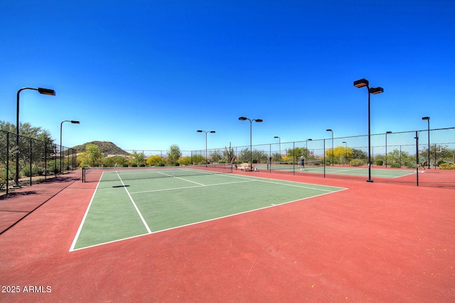 view of tennis court featuring community basketball court and fence