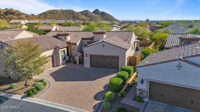 view of front facade featuring an attached garage, a tile roof, decorative driveway, and stucco siding