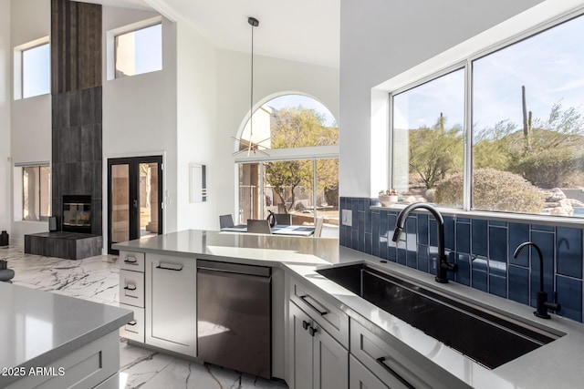 kitchen featuring pendant lighting, sink, backsplash, fridge, and a tiled fireplace