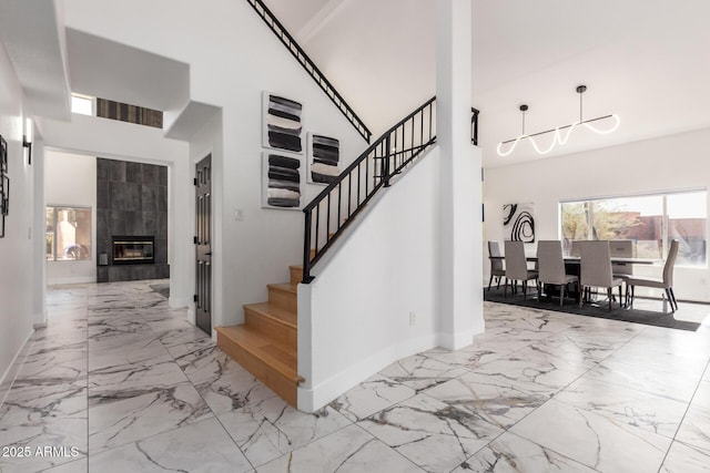 stairs with a high ceiling and a tiled fireplace