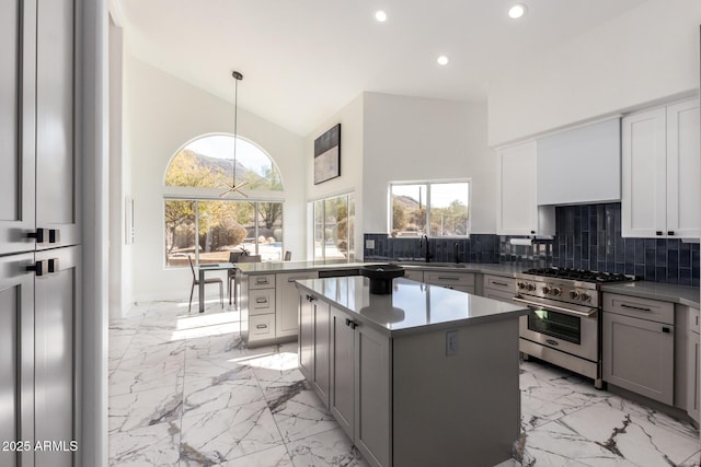 kitchen featuring pendant lighting, sink, a center island, high end stove, and decorative backsplash