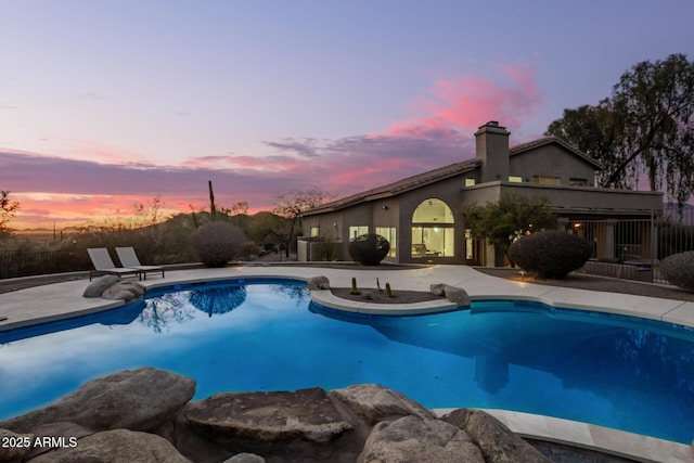 pool at dusk featuring a patio area