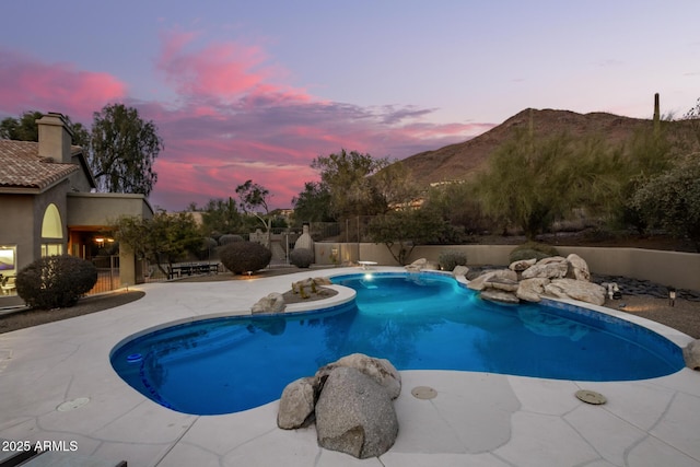 pool at dusk with a mountain view and a patio