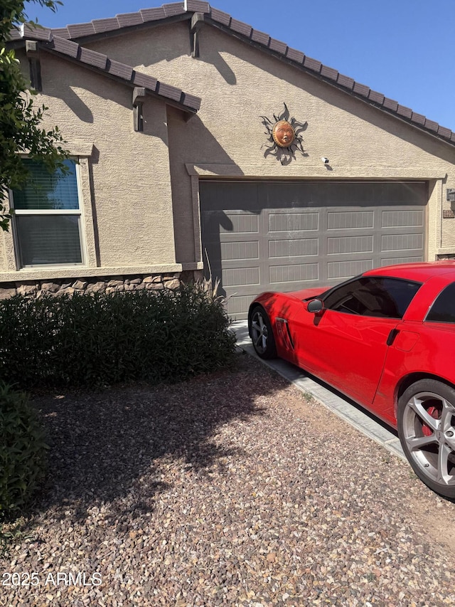 10236 W Wood St, Tolleson, AZ 85353 - view of property exterior with an attached garage, stucco siding, and a tile roof
