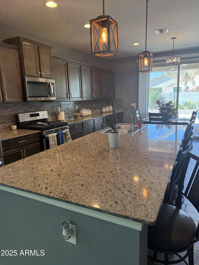10236 W Wood St, Tolleson, AZ 85353 - kitchen with stainless steel appliances, a sink, backsplash, light stone counters, and a large island