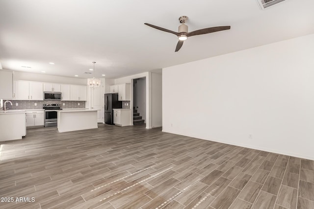 unfurnished living room featuring sink, ceiling fan with notable chandelier, and light hardwood / wood-style flooring