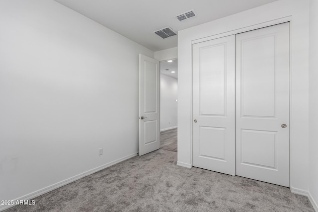 unfurnished bedroom featuring light carpet and a closet