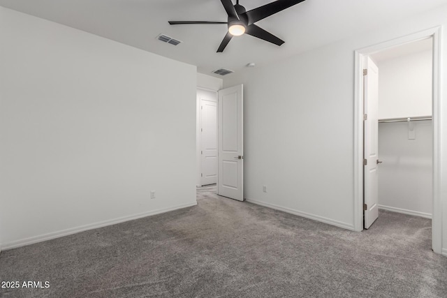 unfurnished bedroom featuring a walk in closet, carpet, and ceiling fan