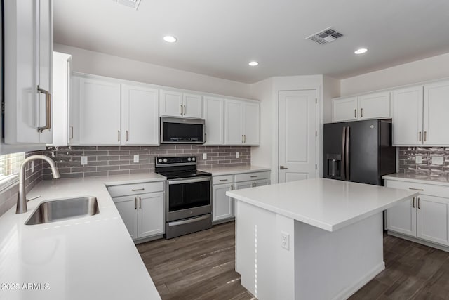 kitchen featuring a kitchen island, sink, white cabinets, dark hardwood / wood-style flooring, and stainless steel appliances