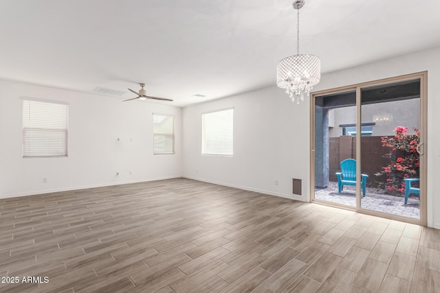 spare room featuring ceiling fan with notable chandelier