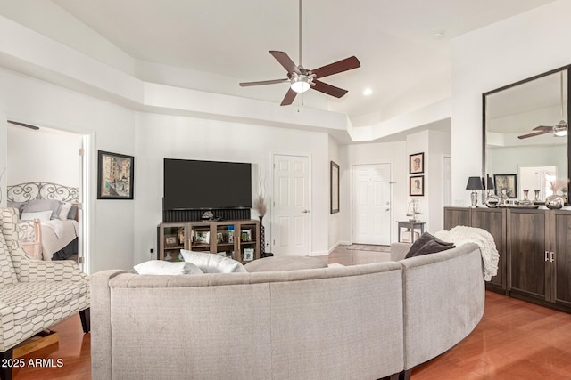 living room with recessed lighting, a ceiling fan, a tray ceiling, and wood finished floors