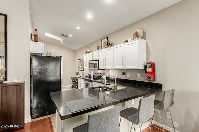 kitchen featuring a breakfast bar area, visible vents, a peninsula, white cabinets, and appliances with stainless steel finishes