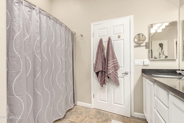 full bath with baseboards, a shower with curtain, vanity, and stone finish floor