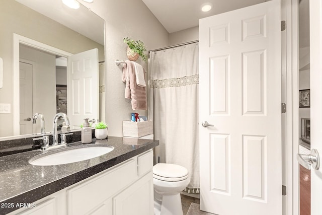 full bath with curtained shower, toilet, vanity, and a textured wall