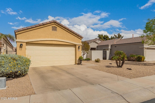 view of front facade with a tiled roof, stucco siding, driveway, and fence