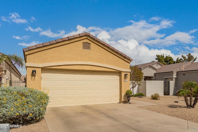 view of front of home featuring fence, an attached garage, stucco siding, concrete driveway, and a tiled roof