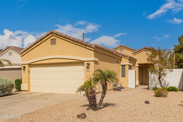 mediterranean / spanish-style home featuring fence, a tile roof, concrete driveway, stucco siding, and an attached garage