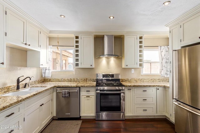 kitchen with dark wood-type flooring, wall chimney exhaust hood, sink, light stone counters, and stainless steel appliances