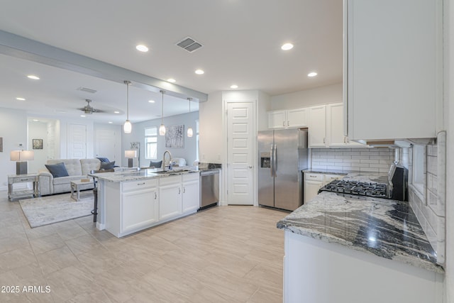 2929 E Mohave Ln, Apache Junction, AZ 85119 - kitchen featuring appliances with stainless steel finishes, a peninsula, white cabinetry, light stone countertops, and open floor plan