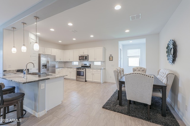 2929 E Mohave Ln, Apache Junction, AZ 85119 - kitchen featuring appliances with stainless steel finishes, a breakfast bar area, light stone countertops, a peninsula, and white cabinetry