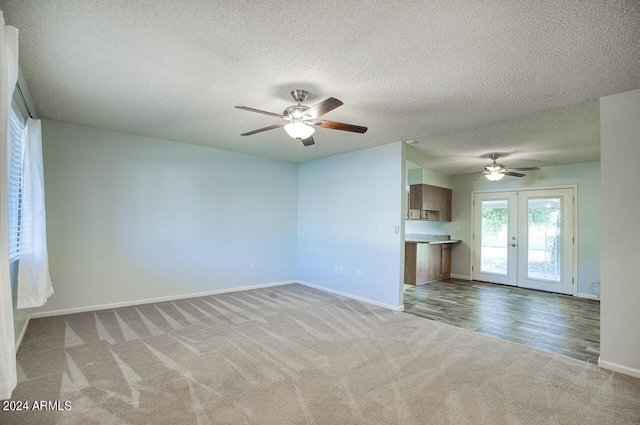 unfurnished living room featuring light carpet, french doors, ceiling fan, and a textured ceiling