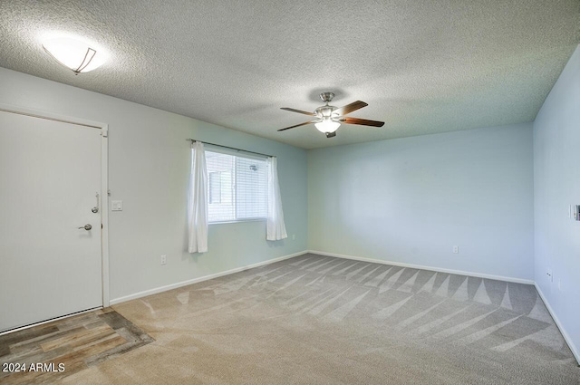 carpeted empty room featuring ceiling fan and a textured ceiling