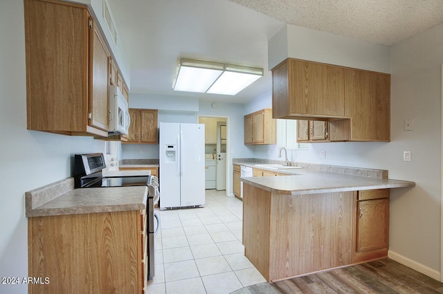 kitchen with white appliances, sink, a textured ceiling, washer / dryer, and kitchen peninsula