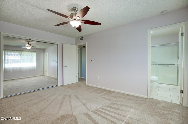 unfurnished bedroom with connected bathroom, ceiling fan, a textured ceiling, light carpet, and a closet