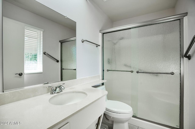 bathroom featuring vanity, toilet, plenty of natural light, and a shower with shower door