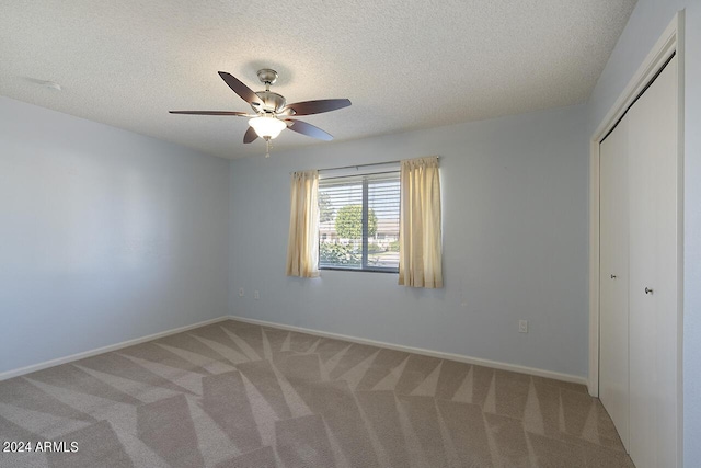 unfurnished bedroom featuring carpet flooring, a textured ceiling, and ceiling fan