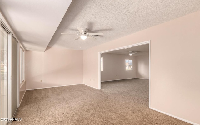 carpeted spare room with a textured ceiling and ceiling fan