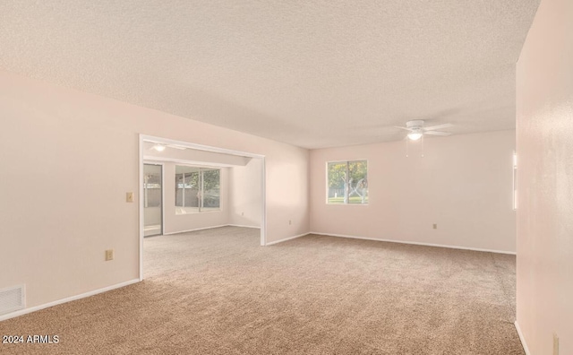 spare room featuring a textured ceiling, light carpet, and ceiling fan