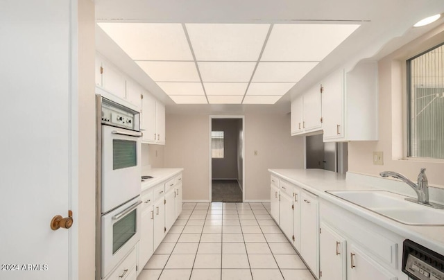 kitchen with white cabinets, sink, and white double oven