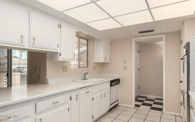 kitchen featuring white dishwasher, white cabinets, sink, and light tile patterned floors