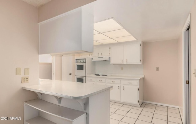 kitchen featuring white cabinets, kitchen peninsula, white double oven, and light tile patterned floors