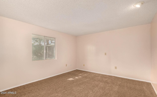 carpeted empty room featuring a textured ceiling