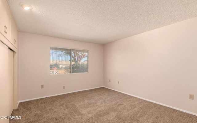 empty room with carpet and a textured ceiling